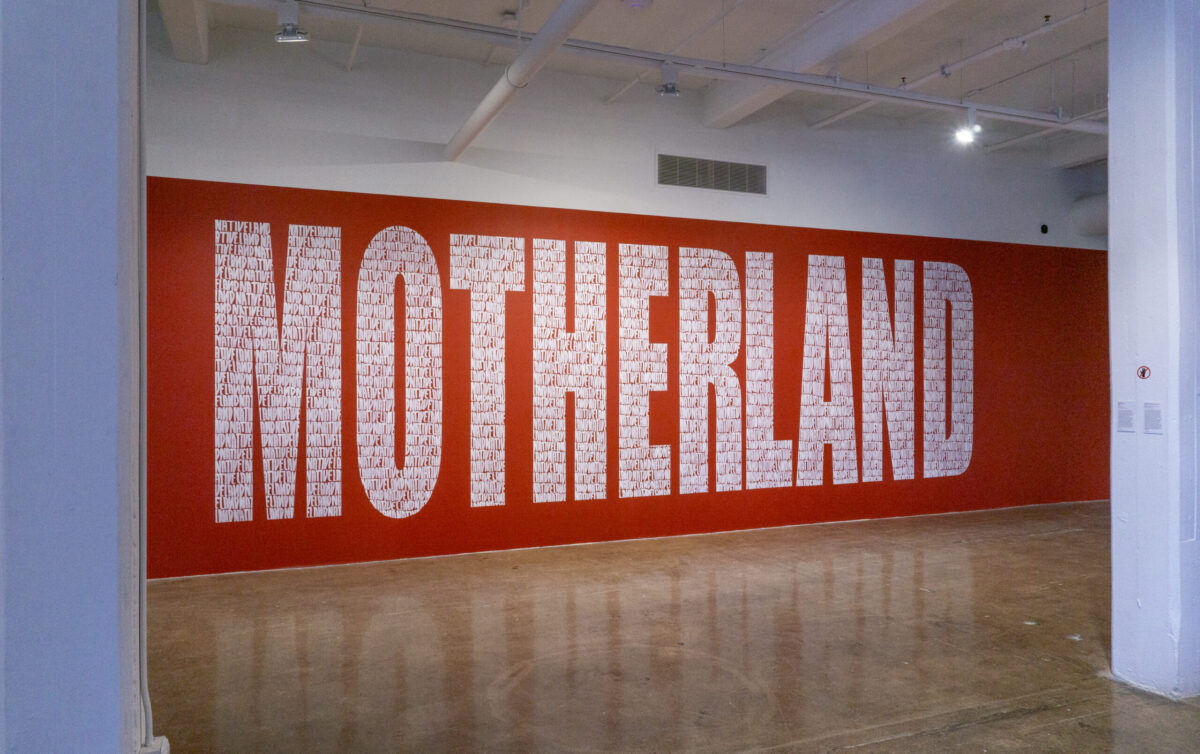 a large wall painted red, with the word 'MOTHERLAND' written across it in big, block letters.